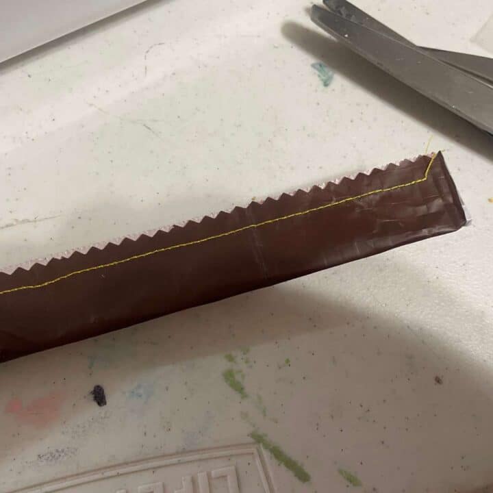 A piece of chocolate is sitting on a table next to a pair of scissors.