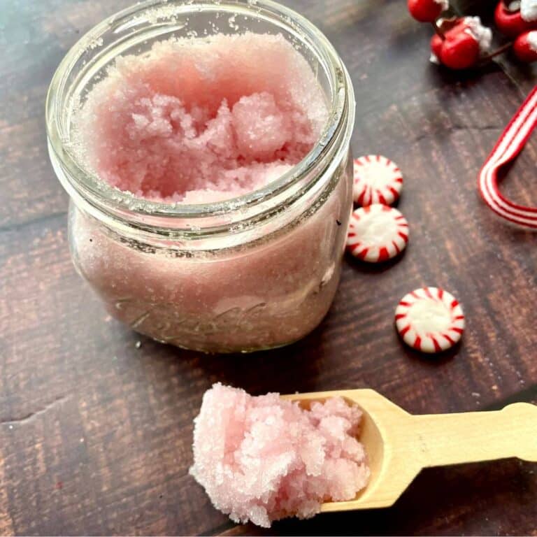 A jar of pink peppermint foot scrub with a spoon and candy canes.
