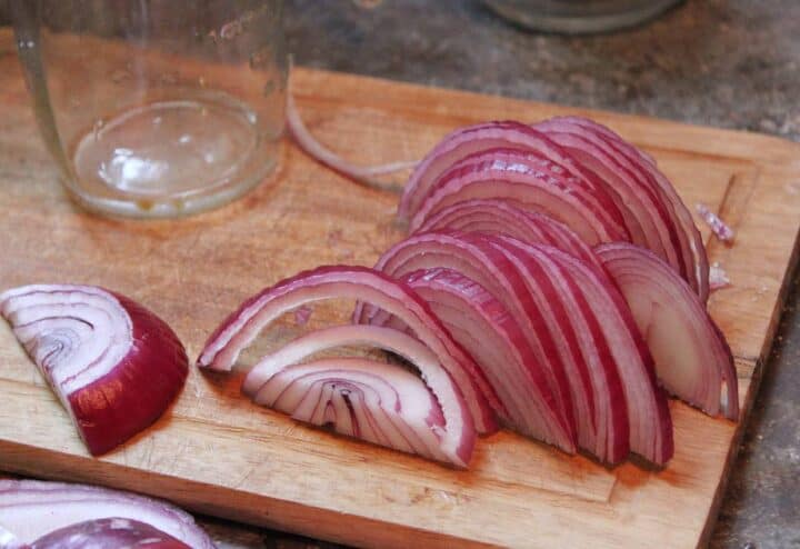 Slicing red onions on wooden cutting board