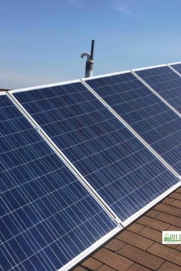 a five panel solar array on a brown shingle roof with a blue sky background