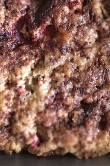 Close-up of a baked strawberry rhubarb dessert with a crumbly texture and visible berries.