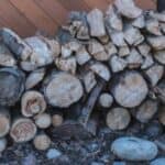 A pile of wood is stacked in front of a house.