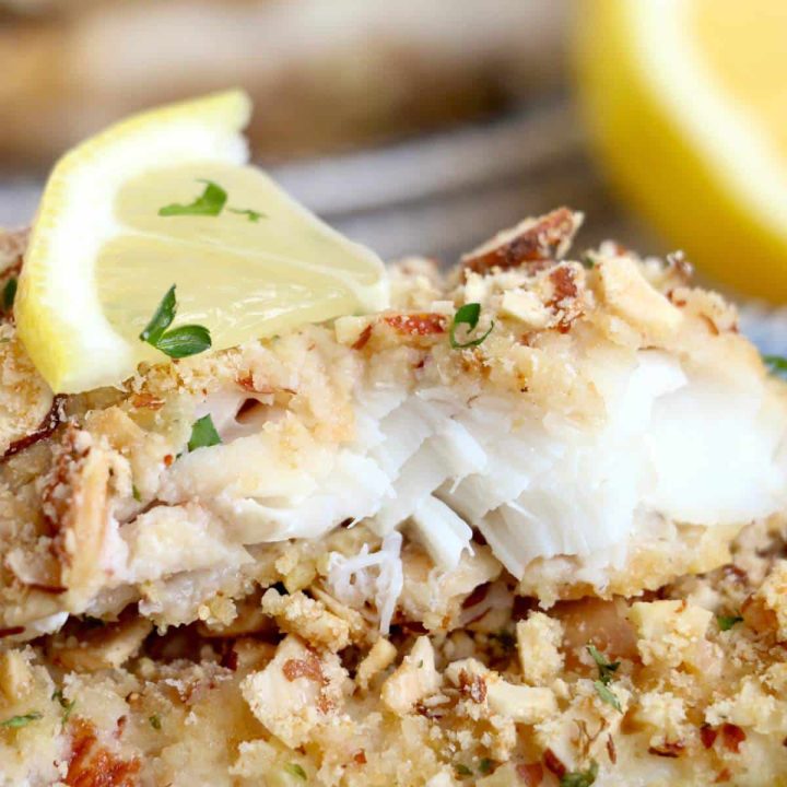 A close up of a piece of walleye fillet with a lemon wedge on top.