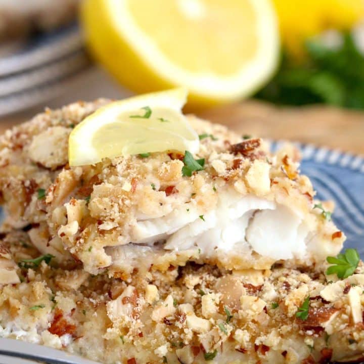 Walleye fish fillets with a lemon wedge on a plate.
