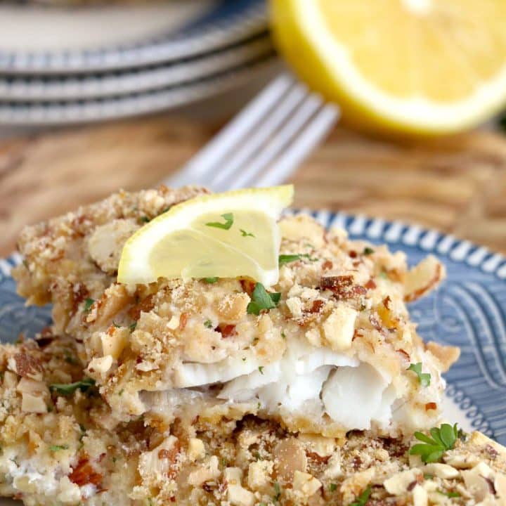 Walleye fish fillets with almond crust and lemon wedges on a plate.