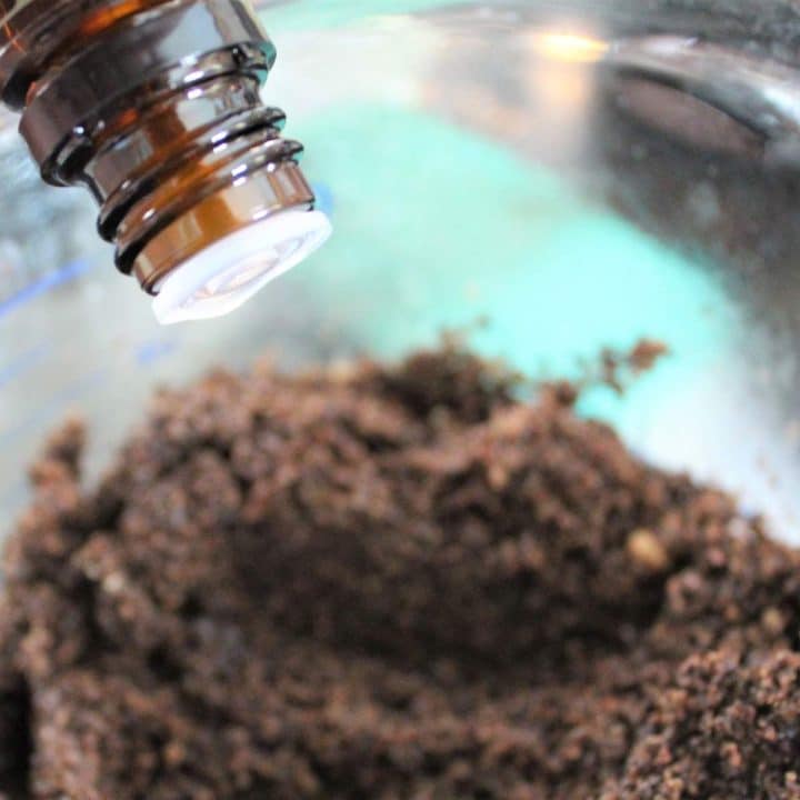 A bottle of essential oil is being poured into a bowl of mixture of sugar and cocoa.