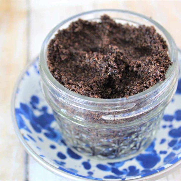 A jar of scrub mixture sitting on a blue and white plate.