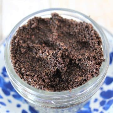 A jar of coffee granules on a blue and white plate, perfect for making a coffee brown sugar scrub.