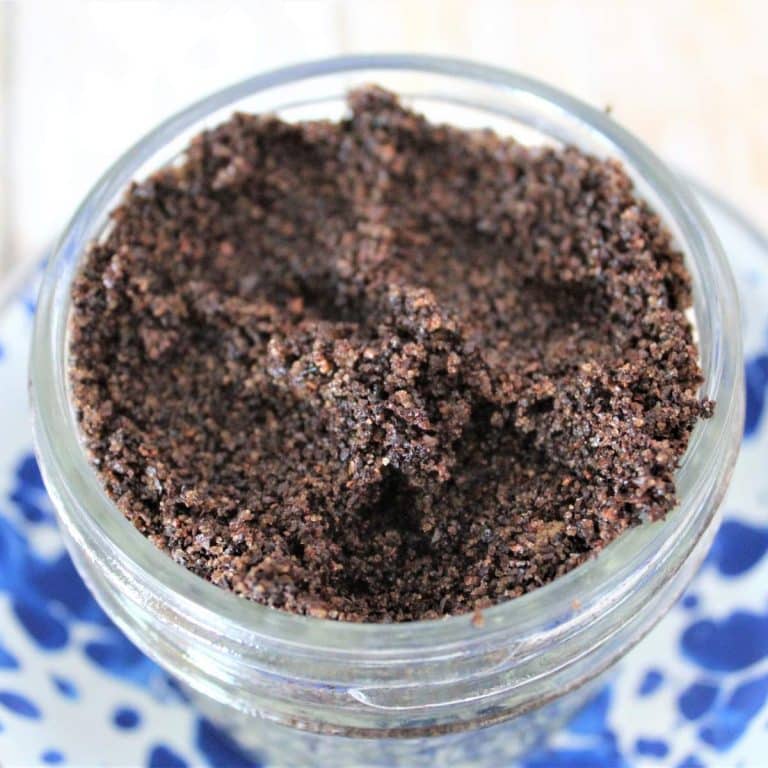 A jar of coffee granules on a blue and white plate, perfect for making a coffee brown sugar scrub.
