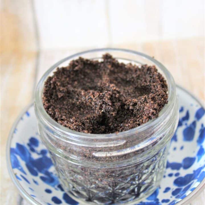 A jar of scrub mixture sitting on a blue and white plate.