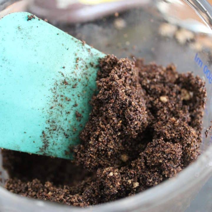 A green spatula is being used to stir a mixture of brown sugar and cocoa powder in a bowl for coffee brown sugar scrub.
