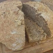A loaf of bread on a cutting board with a knife.