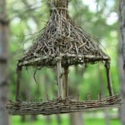 A handcrafted miniature twig gazebo suspended amongst trees.