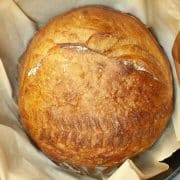 A loaf of bread sitting in a pan on a wooden table.