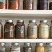 Many jars of different kinds of spices on a shelf.