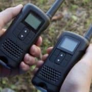 Two hands holding two walkie talkies.