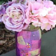 A decorated jar vase with pink and purple flowers.