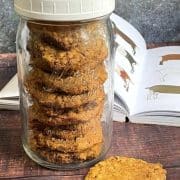 A jar of cookies sitting on a table next to a book.
