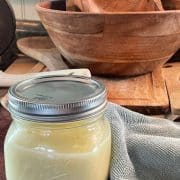 A jar of butter on a wooden cutting board.