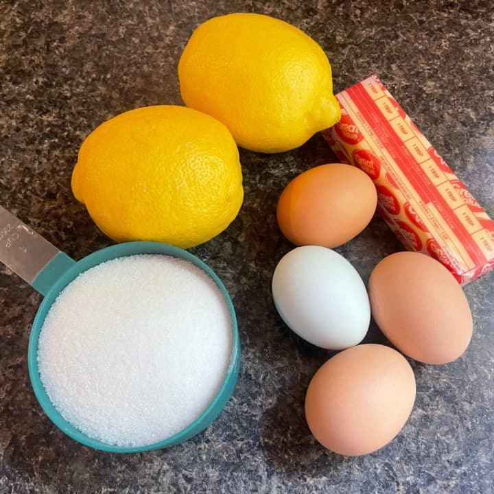 Eggs, sugar and lemons on a counter.