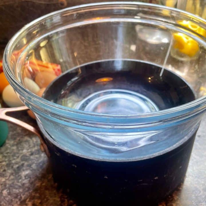 A glass bowl and a black sauce pans on a counter.