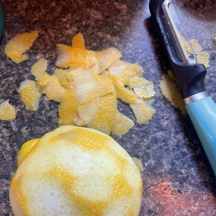 Peeling a lemon with a citrus peeler.