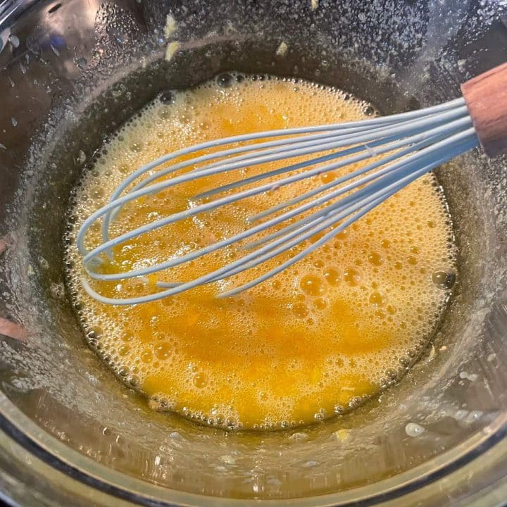 A whisk in a bowl of egg.