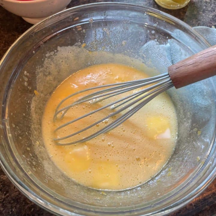 A bowl of batter with a whisk in it.