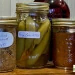 4 ball mason jars with different preservatives and golden lids.
