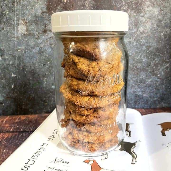 A jar of goat treats sitting on a table next to a book.
