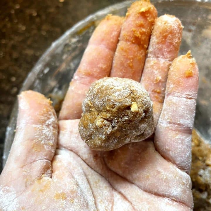 A person's hand holding a ball of dough.